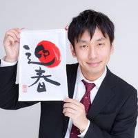 新年のご挨拶と迎春の巾着を掲げるビジネスマンの写真