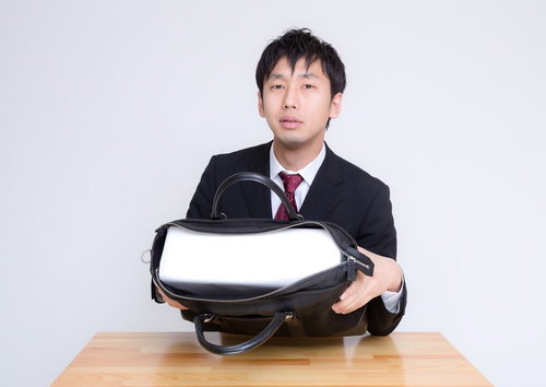札束に見立てた白い箱がかばんに入ったと説明するビジネスマン