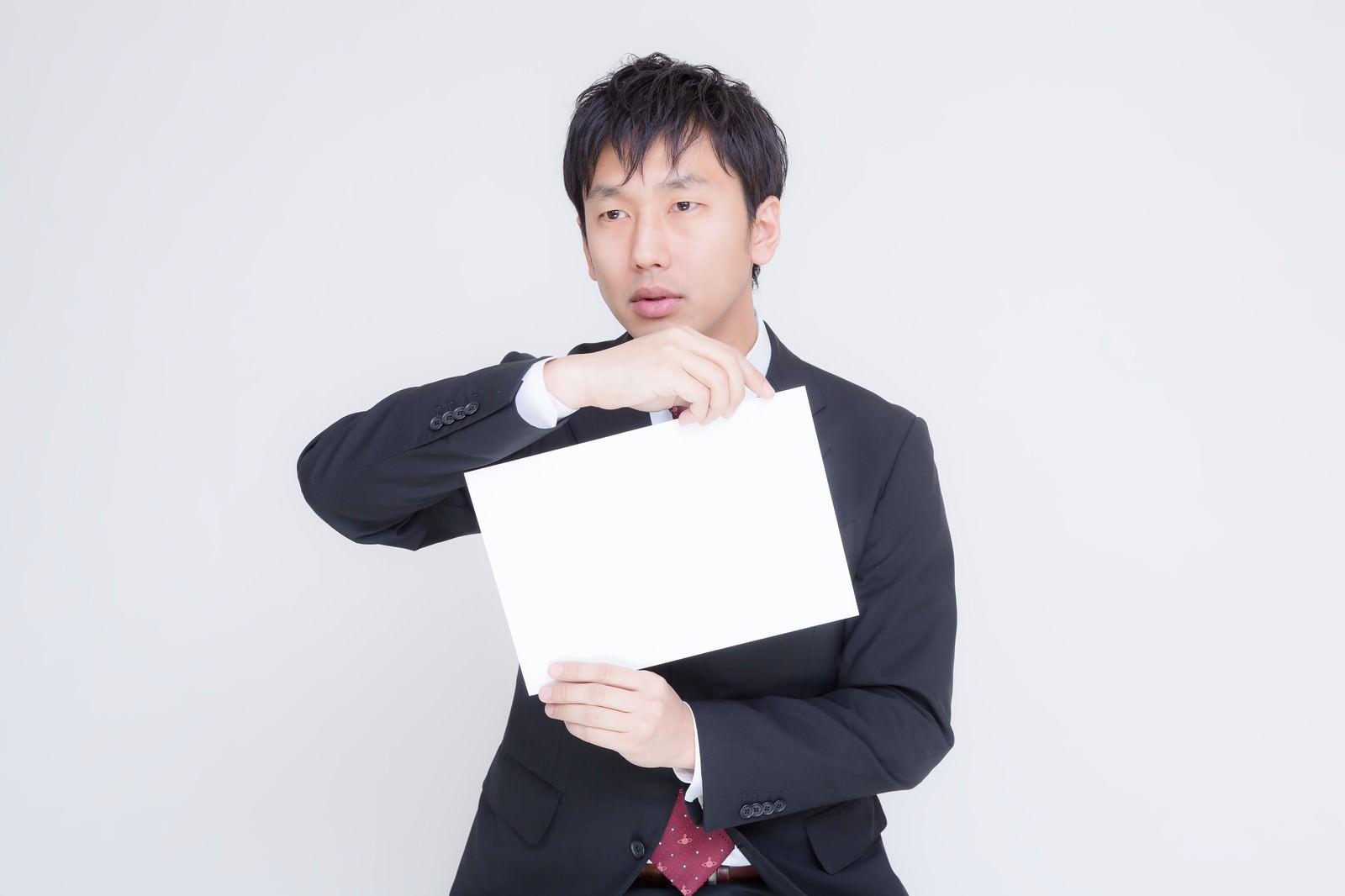白いボードを持って演説するスーツの男性［モデル：大川竜弥］
