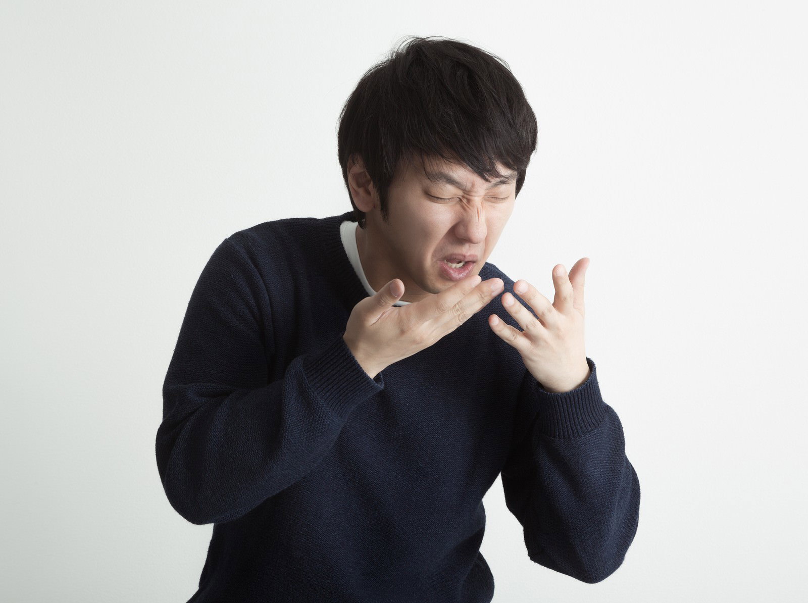 くしゃみをして両手を顔の前に上げて叫ぶ男性［モデル：大川竜弥］