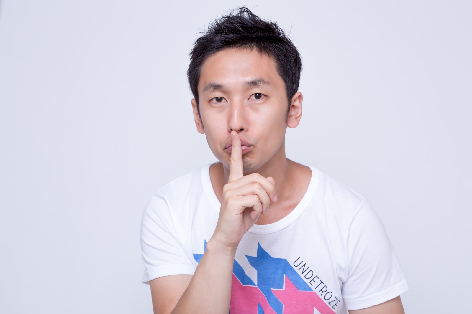 人差し指を口に当てて沈黙を示す男性［モデル：大川竜弥］