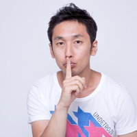 人差し指を口元に当てて「内緒」のポーズの男性の写真