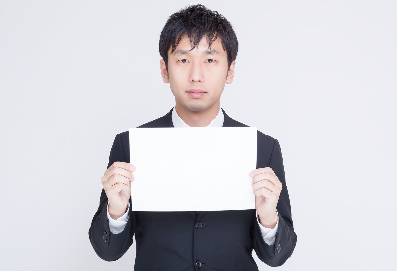 ホワイトボードを掲げるスーツ姿の男性［モデル：大川竜弥］
