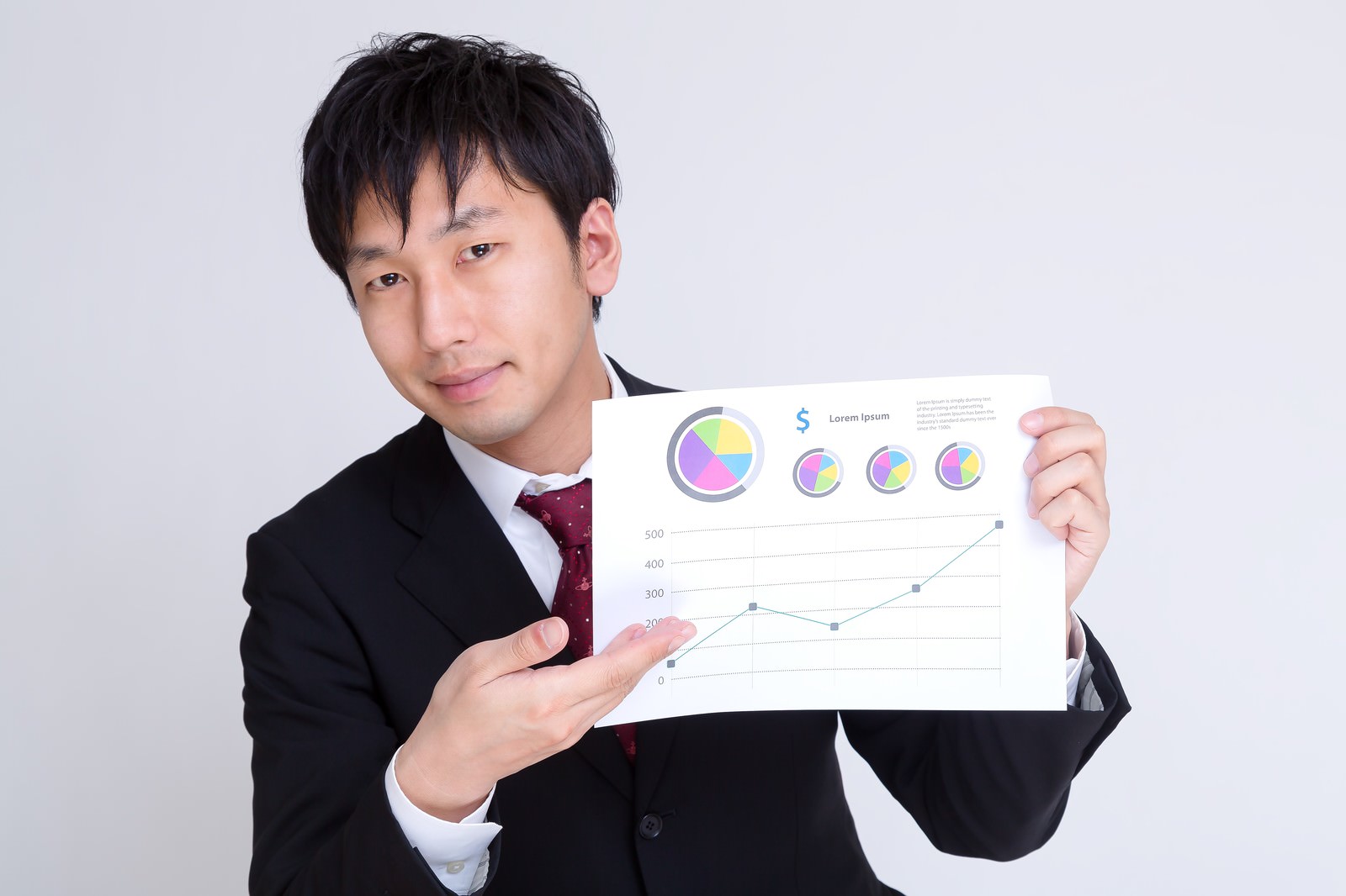 グラフと円グラフの資料を持ち、提案するサラリーマン［モデル：大川竜弥］