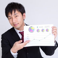 グラフ資料を指して説明するスーツの男性の写真