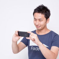 スマホを横向きに持って画面を見る男性の写真