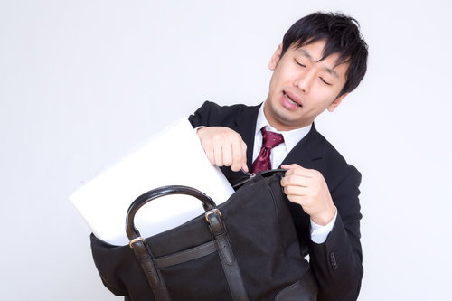 縦なら入るとファスナーを閉めようとするビジネスマン