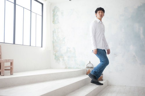 新居の下見で階段を見上げる男性、白シャツとジーンズ姿