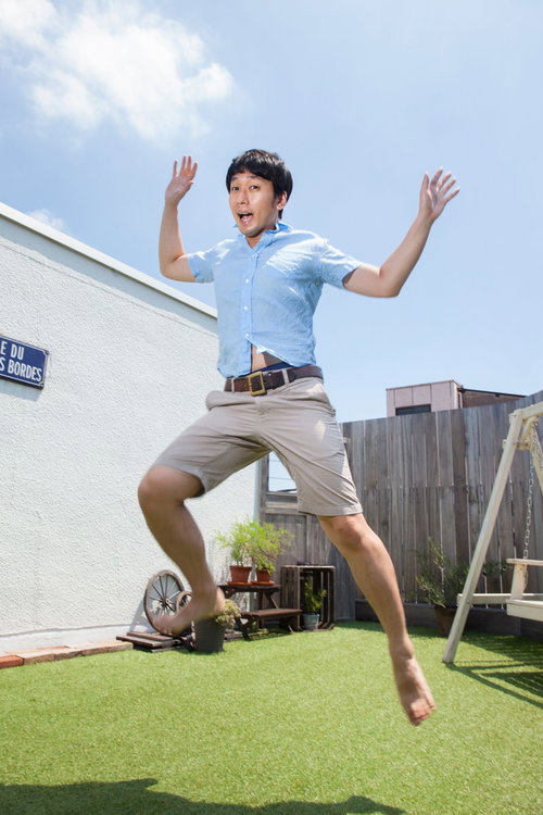 夏休みに庭でジャンプして喜ぶ男性の晴れた日の一瞬