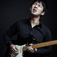 黒いオーダーメイドシャツを着てチョーキングするブルースギタリストの写真