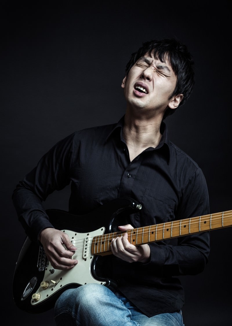 黒いシャツを着てギターをチョーキングで演奏する男性ミュージシャン