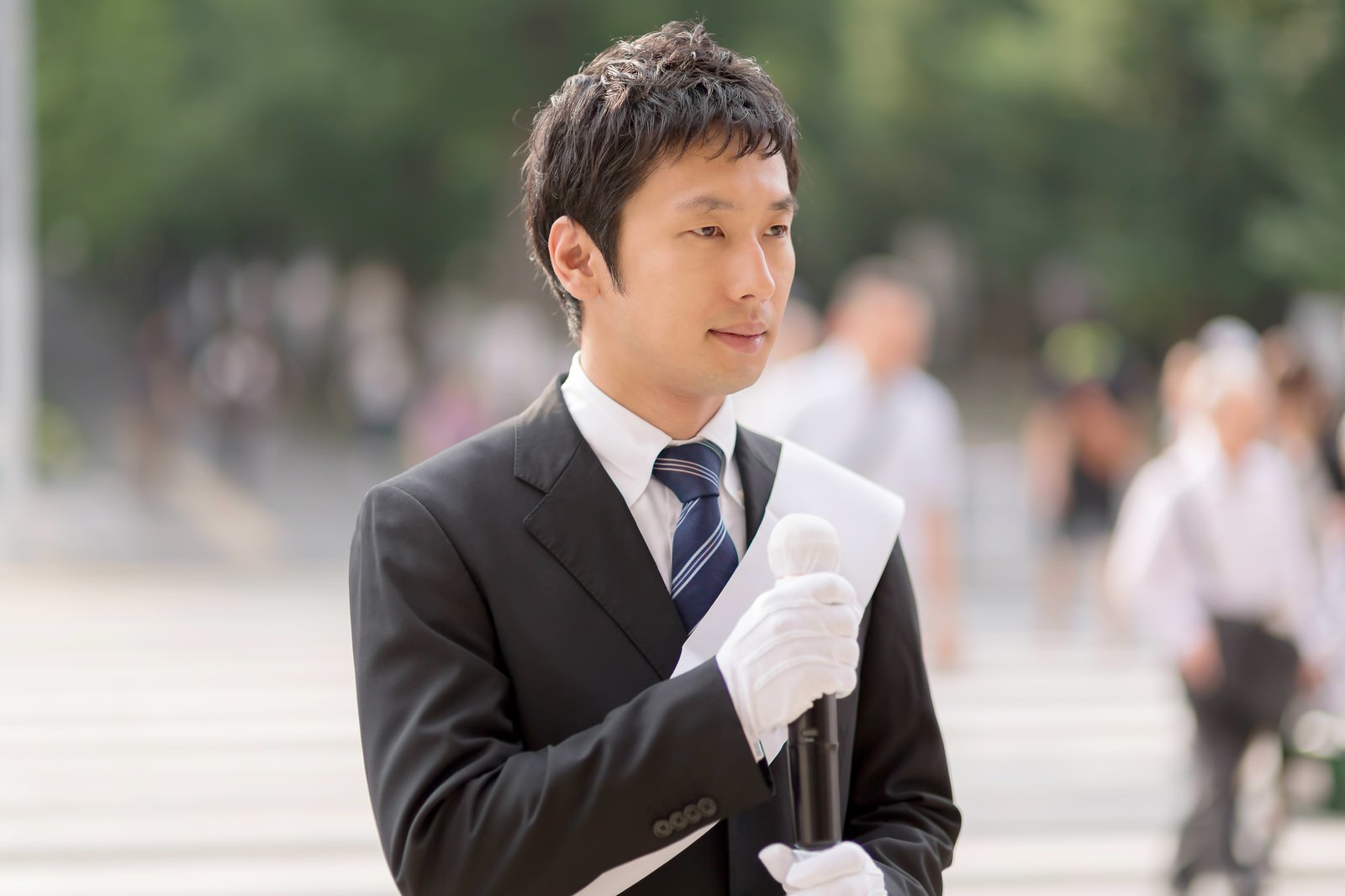 人ごみの中で書類を持つ白い手袋の選挙活動の男性［モデル：大川竜弥］
