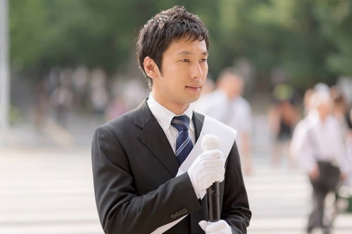 人ごみの中で書類を持つ選挙活動の男性