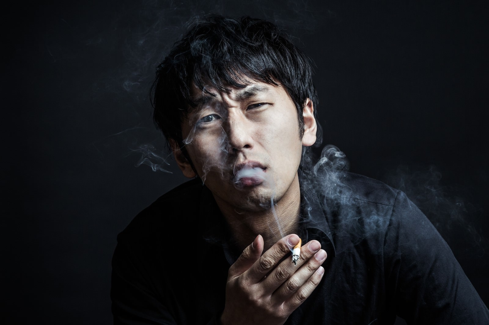 煙草を持ったまま怒鳴る男性。激怒した表情と喫煙の動作を捉えた一枚［モデル：大川竜弥］