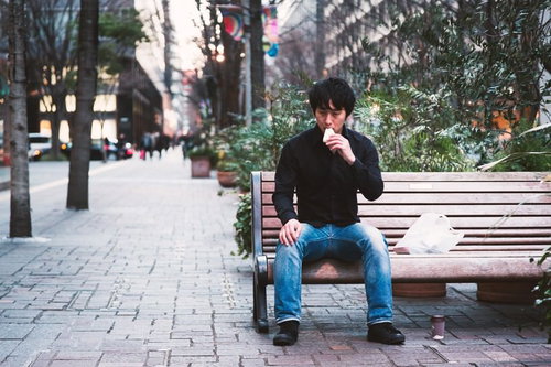 ベンチで一人ランチをとる男性