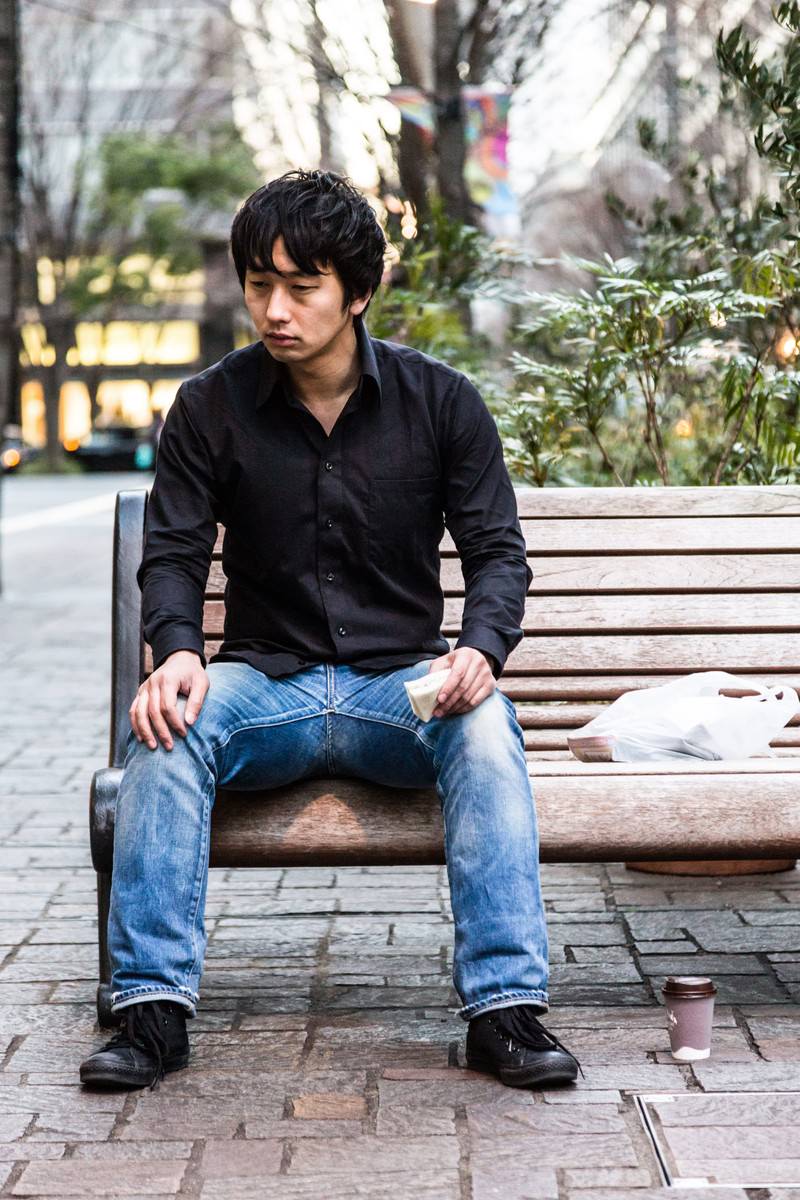 ベンチでひとりランチをとる男性［モデル：大川竜弥］