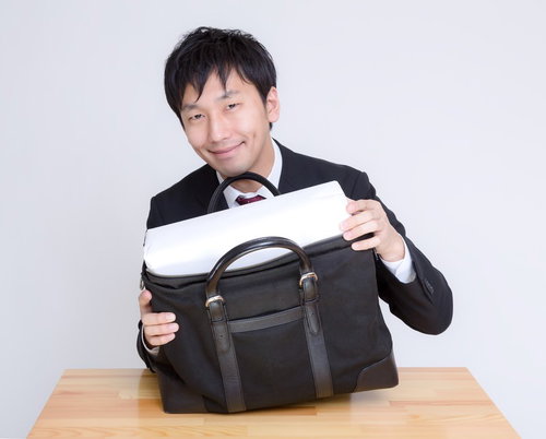 バッグから白い箱を取り出して見せる男性