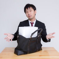 札束に見立てた箱がかばんに入らない男性の写真
