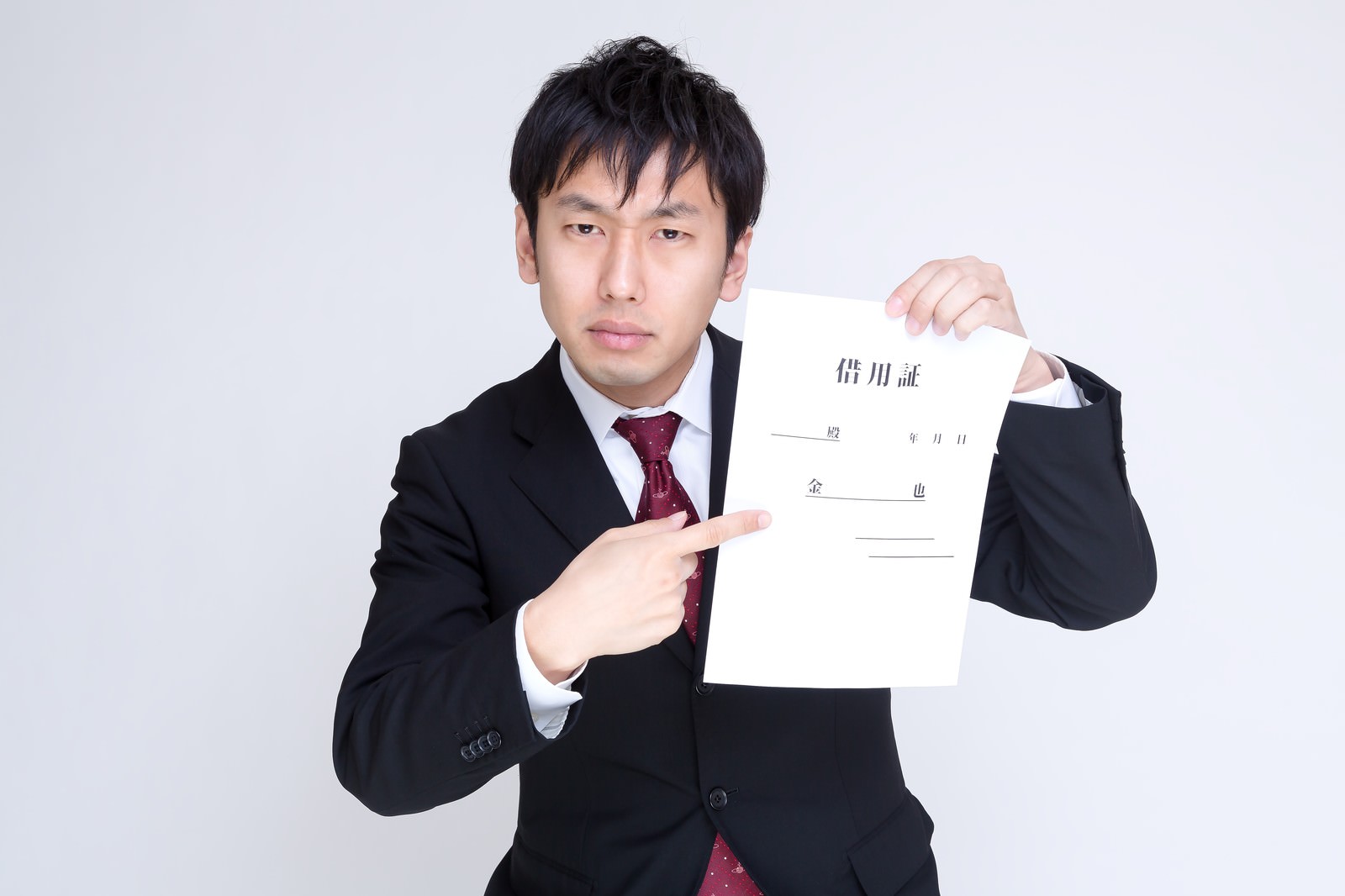 借用証を指して怒った表情の男性［モデル：大川竜弥］