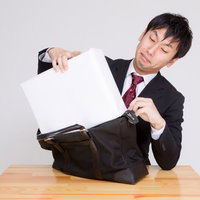 札束に見立てた白い箱をかばんに押し込む男性の写真