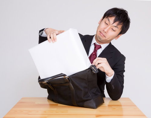 札束に見立てた白い箱をかばんに押し込む男性
