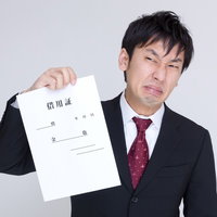 借用証を片手に渋い表情のスーツの男性の写真