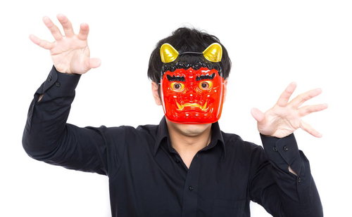 赤い鬼面と黄色い角で両手を広げて威嚇する黒い長袖の人物