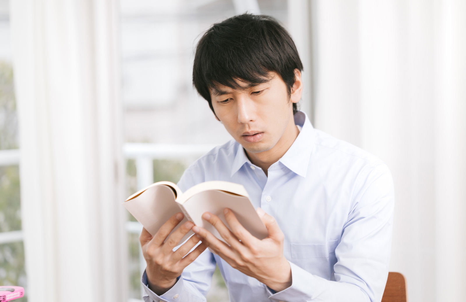 参考書を首を傾けて読み返す男性［モデル：大川竜弥］