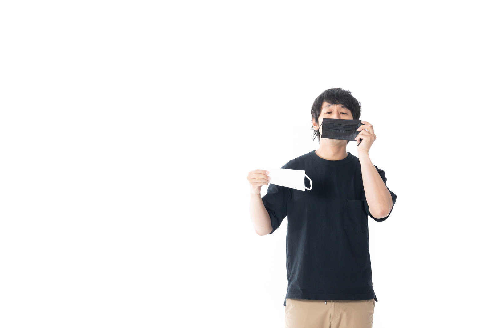 白背景でマスクを両手に持つ黒いTシャツの男性［モデル：大川竜弥］