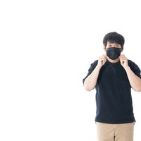 黒マスクを調整する男性の感染症予防ポーズの写真