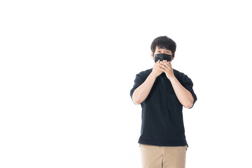 黒マスクをした匿名の男性が両手でマスクを押さえるポーズ