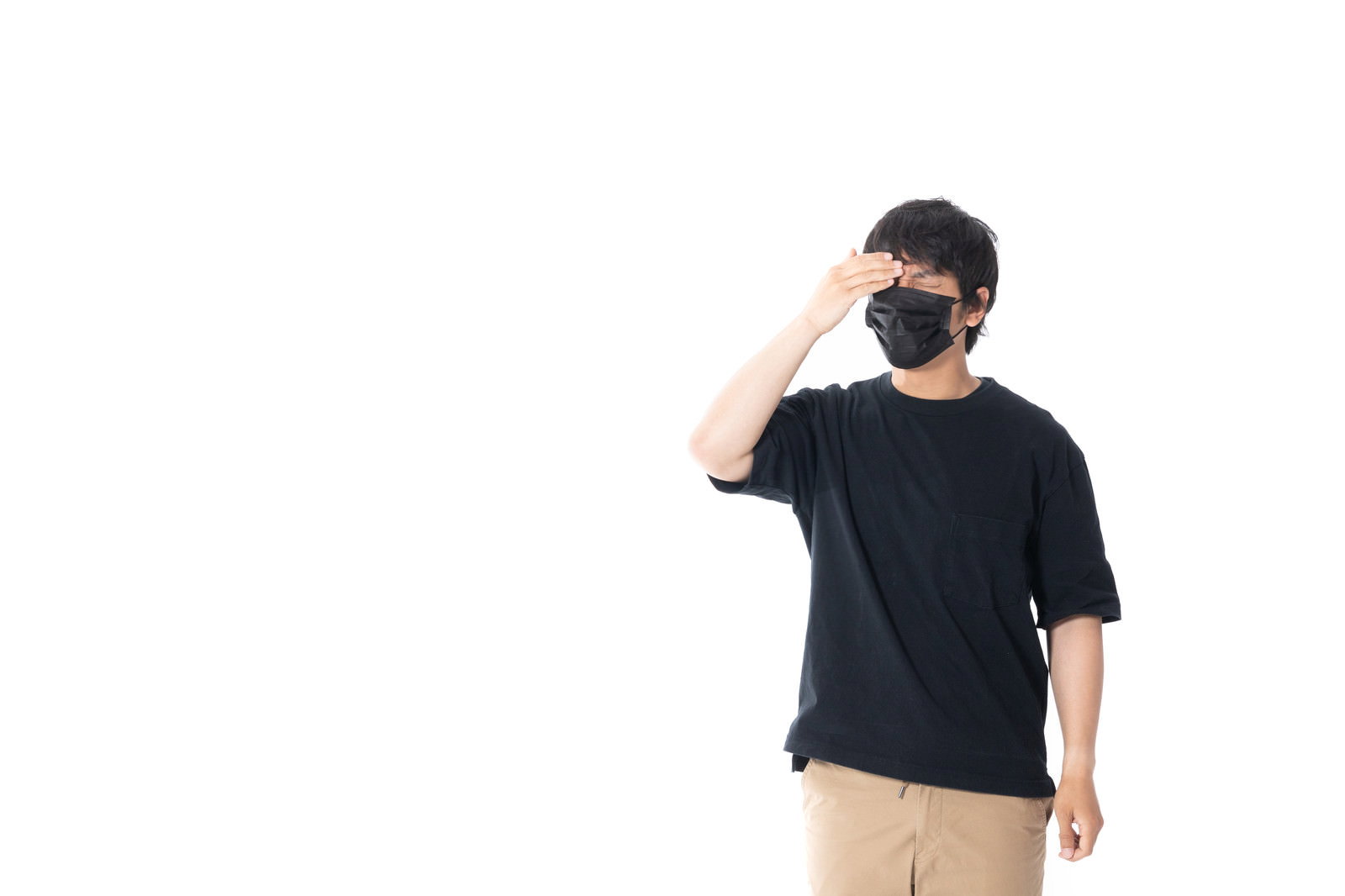 黒いマスクを着用し、両手で頭を抱えて頭痛に悩んでいる男性［モデル：大川竜弥］