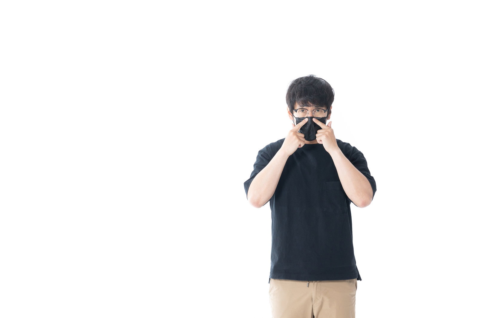 黒いマスクを着用した男性が白い背景の前に立っている［モデル：大川竜弥］