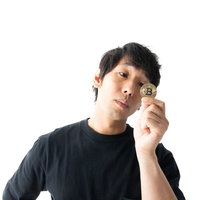 ビットコインのシンボルを手にして見つめる男性の写真