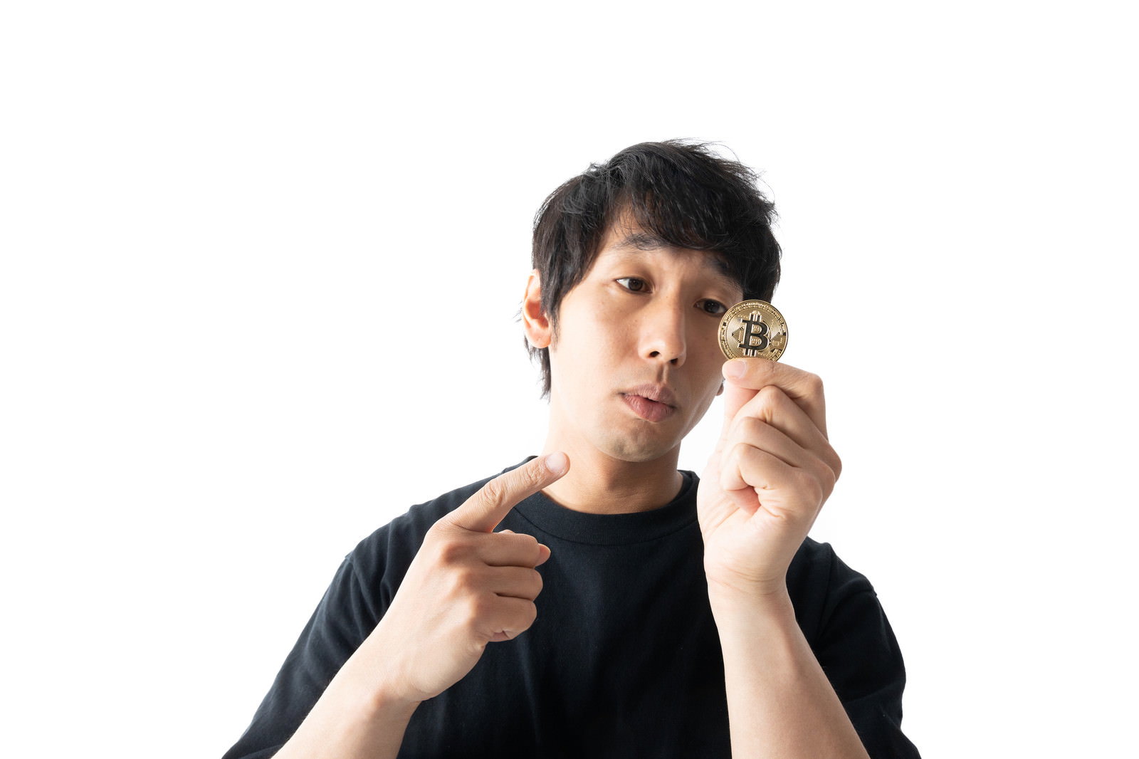 ビットコインのコインを指差している黒いTシャツの男性［モデル：大川竜弥］