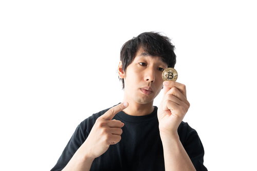 1BTCのゴールドコインを指差す男性の投資