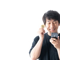 スマホでビットコイン価格を確認して笑う男性の写真