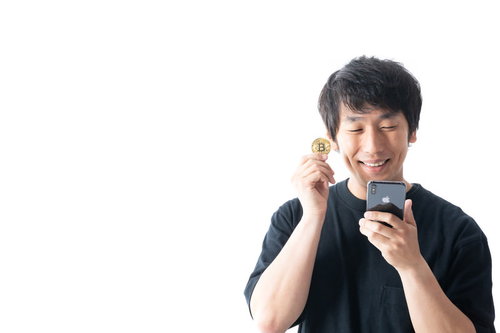 スマホでビットコイン価格を確認して笑う男性