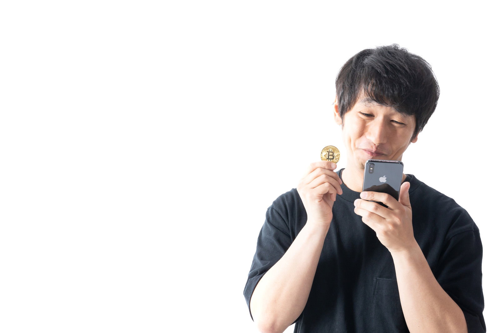 スマートフォンを持ってビットコインの収益に喜ぶ黒いTシャツの男性［モデル：大川竜弥］