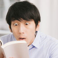 誤植を発見し目が飛び出る勢いで驚く校閲ボーイの写真