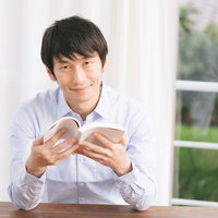 書評記事を執筆するプロブロガー男性が本を手に笑顔の写真