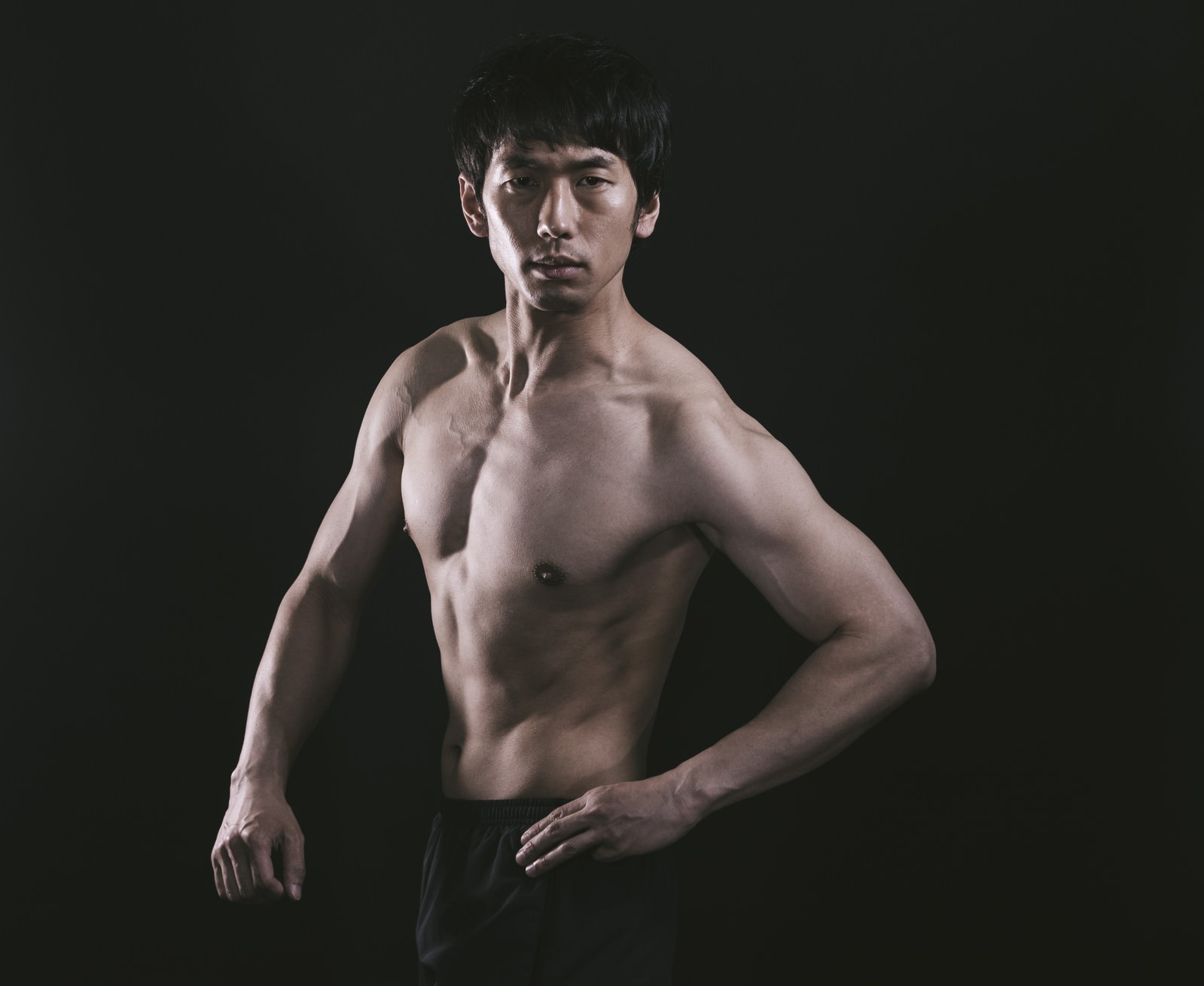 振り返りながらポーズを決める筋肉質な上裸の男性［モデル：大川竜弥］
