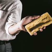 新しいあぶらあげを自慢げに見せてくる会社員の写真