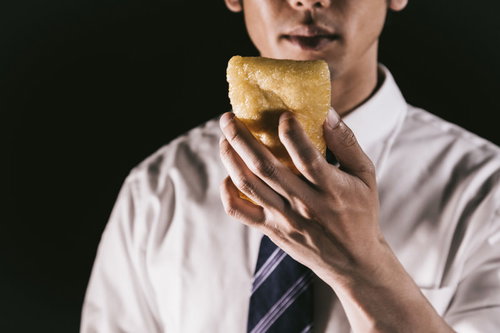 6インチサイズのあぶらあげをほおばるサラリーマン