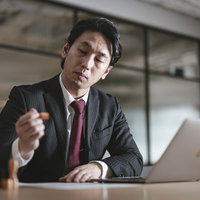 判子を押すだけで出勤する役員男性がサインする契約書類の写真