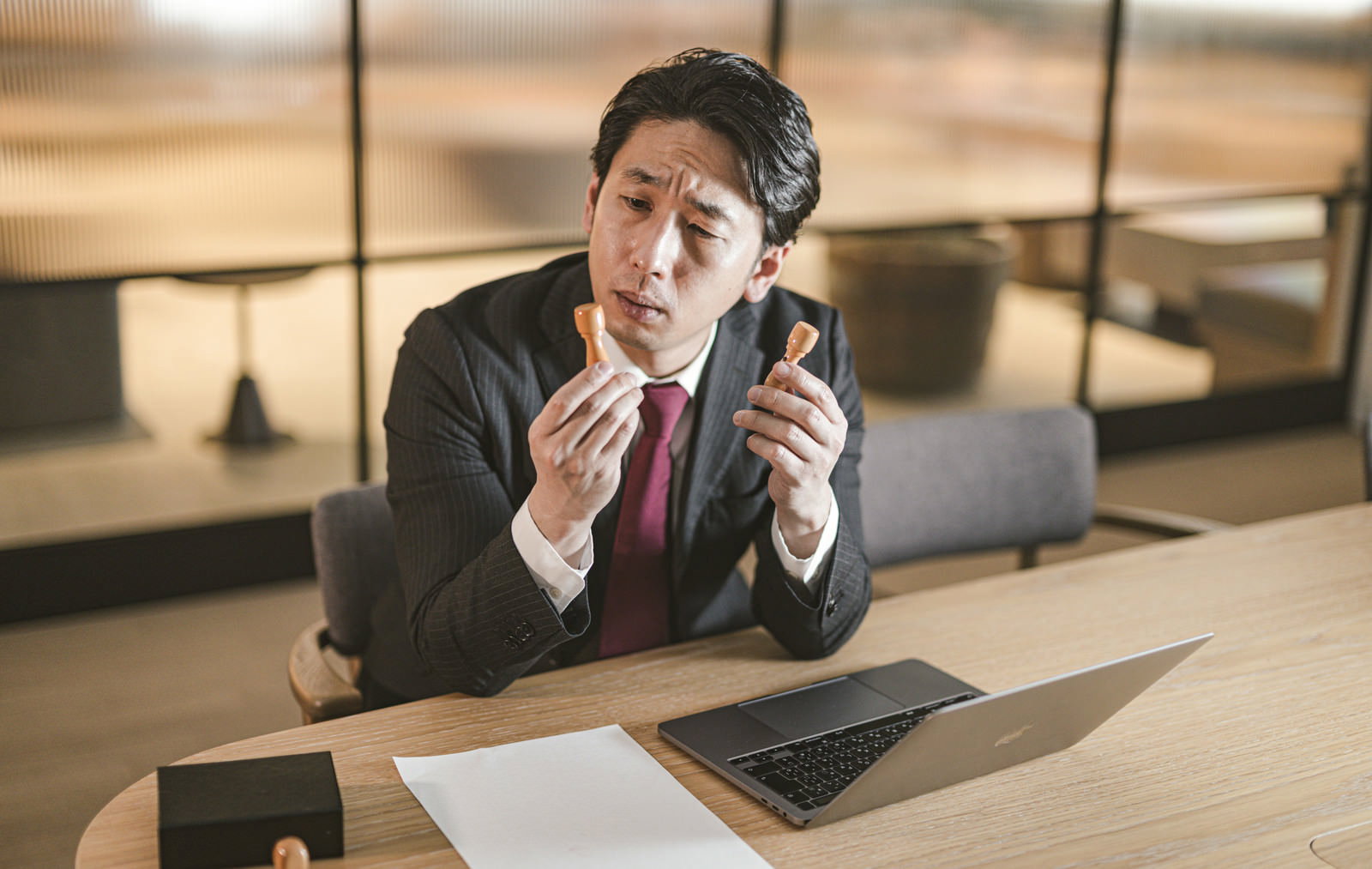 両手にハンコを持ち困惑する男性社員［モデル：大川竜弥］