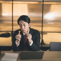 契約するべきか悩む会社役員が印鑑を手に持ち考えるの写真