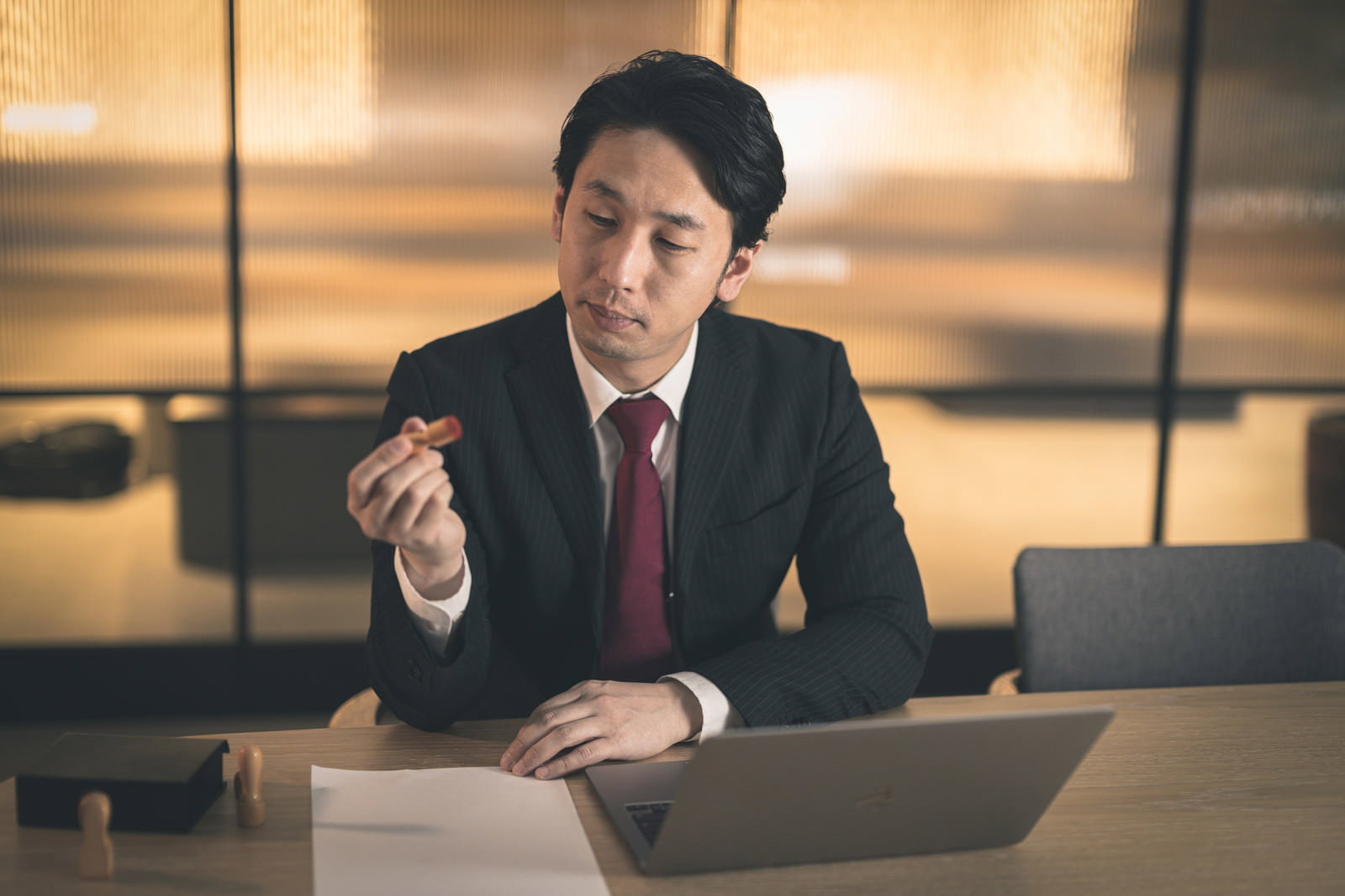 オフィスで契約書に印鑑を押すスーツ姿の会社役員男性［モデル：大川竜弥］