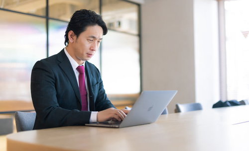 広い会議室でノートパソコンを使ってリモートワークする男性