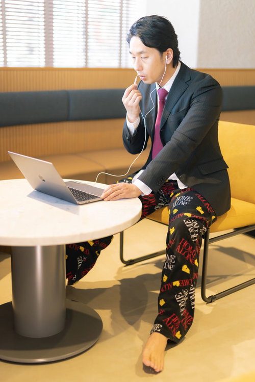 上半身スーツ、下半身パジャマ姿でリモートワークする男性